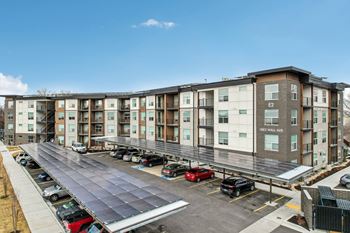 A parking lot in front of a multi-story apartment building.